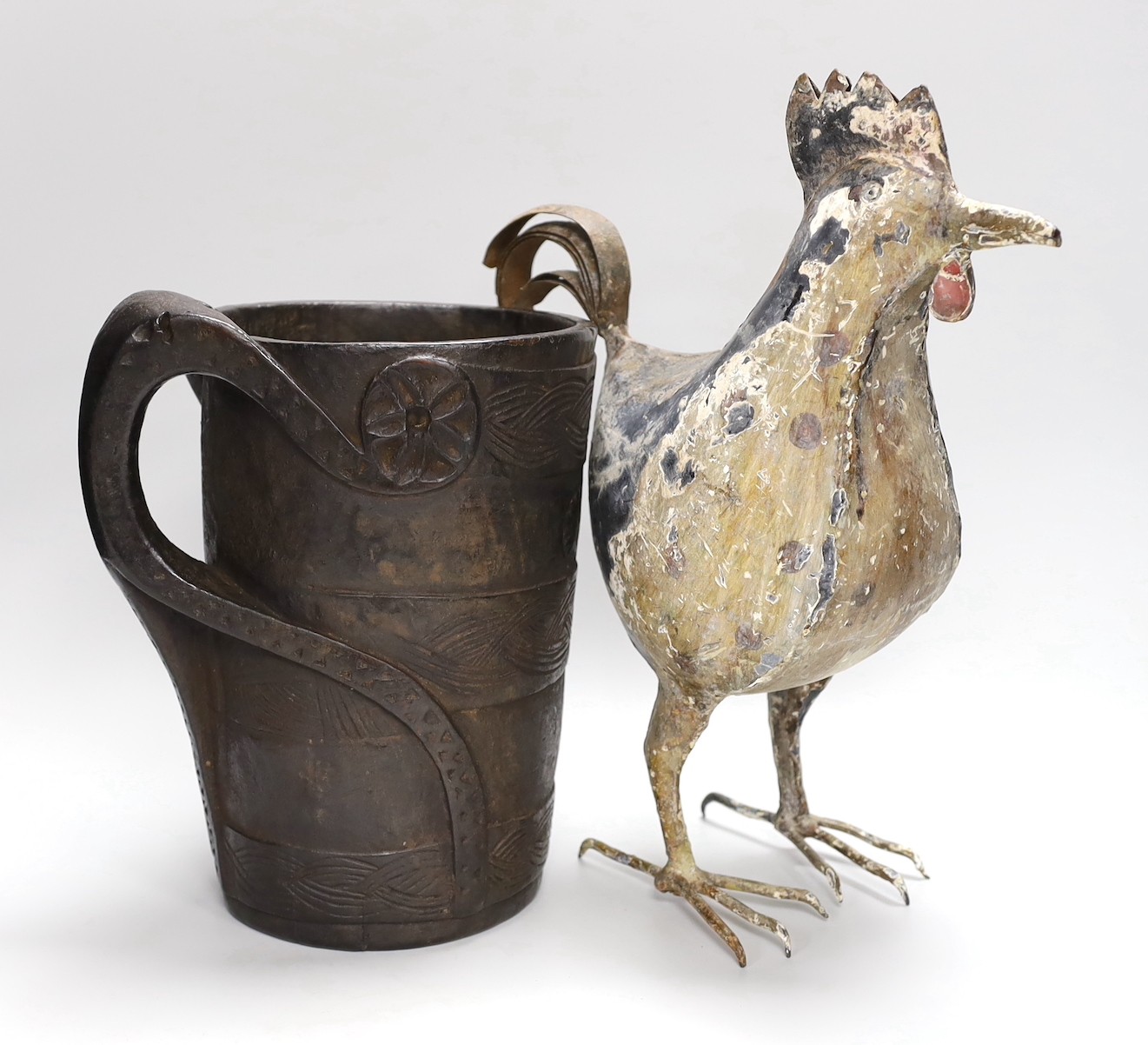 An 18th century Scandinavian carved wood tankard and a 19th century painted tin plated iron model of a cockerel, 36.5cm high.
